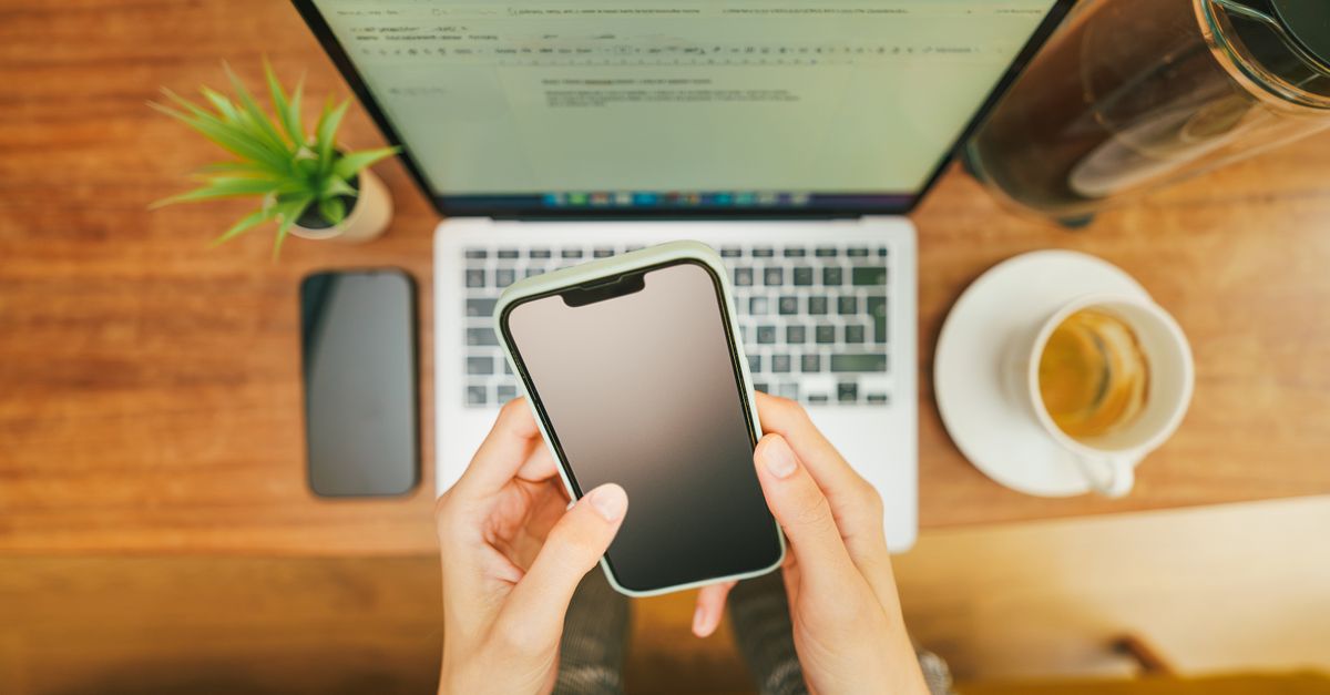 A person drafting a polite message on their phone at a kitchen table.